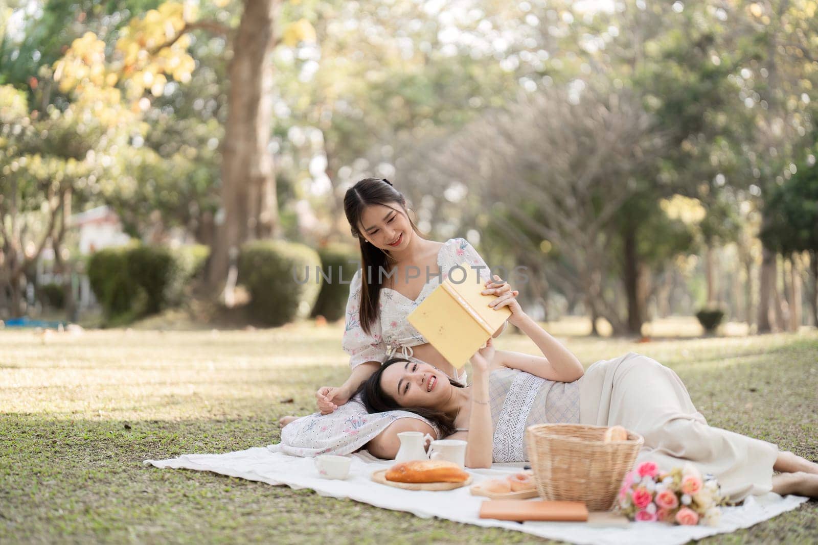 Two best friend do holiday activities, eat snacks, read books, and have picnics in the park to relax together..