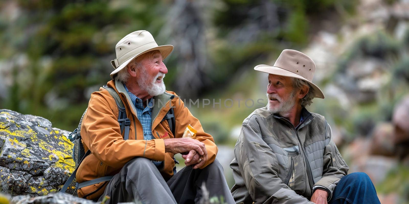 Cheerful senior couple of friends in mountain excursion laughing while sitting to rest, enjoying healthy lifestyle in nature. High quality photo