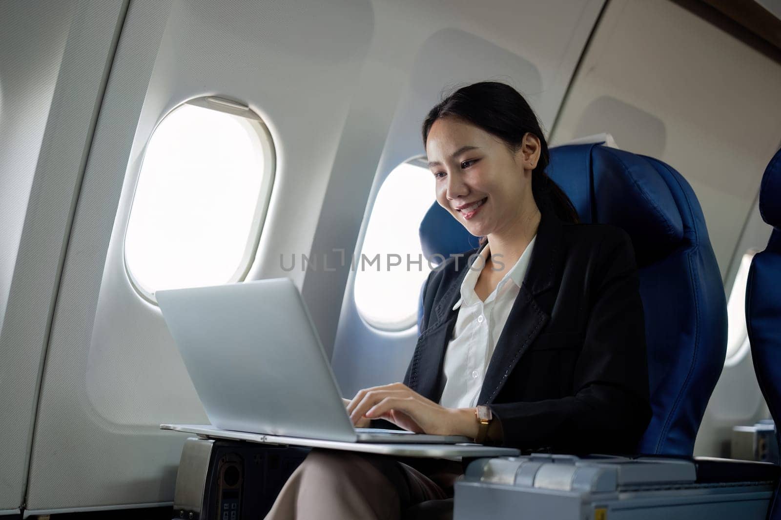 A young business woman travels to work outside the city by flying in business class. and work on airplanes with laptops.