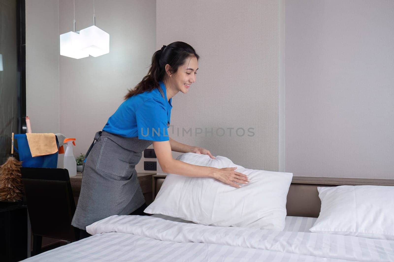 The bedroom maid is cleaning the bed and preparing the bedding..