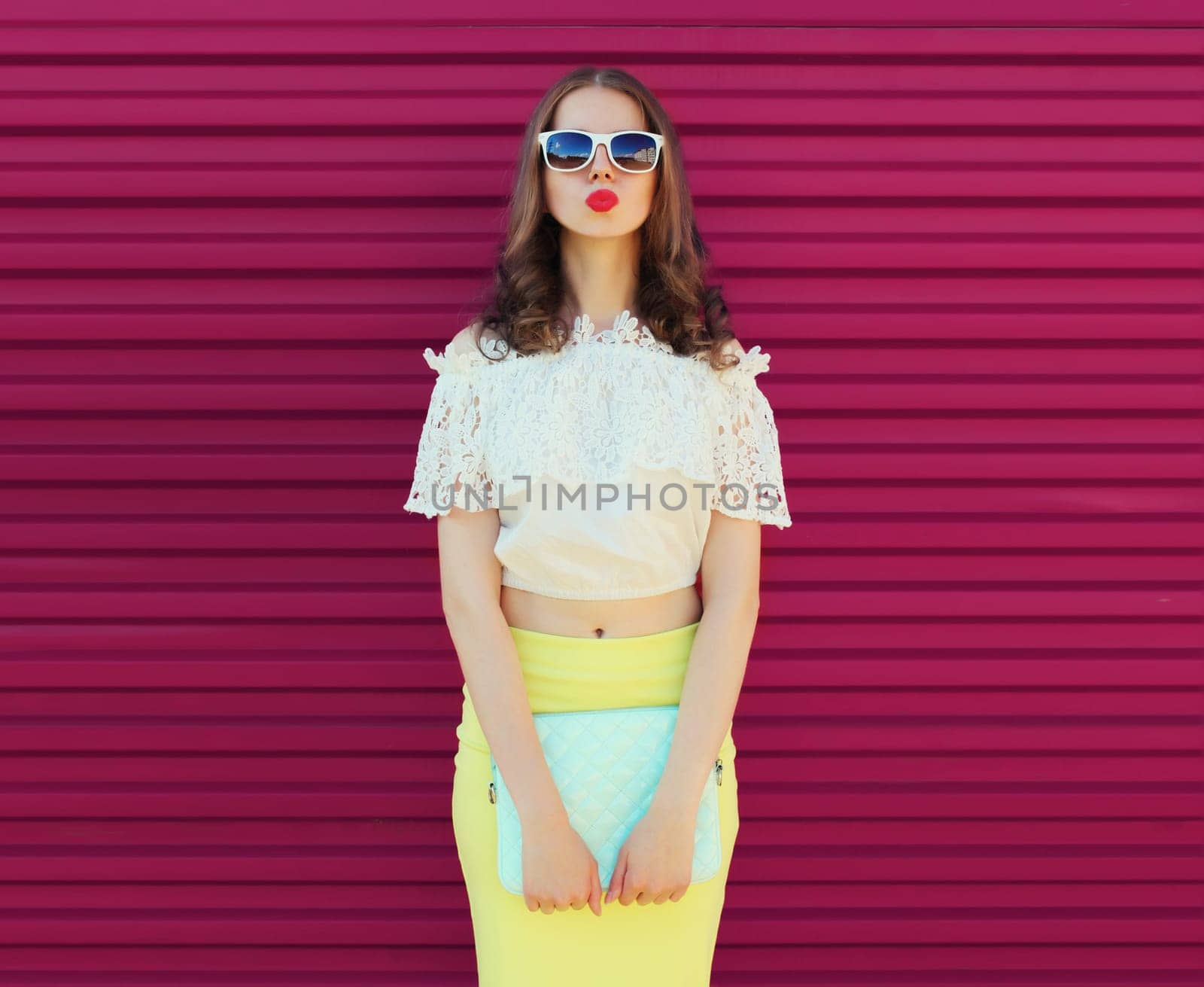 Beautiful caucasian young woman model posing with handbag clutch on pink background