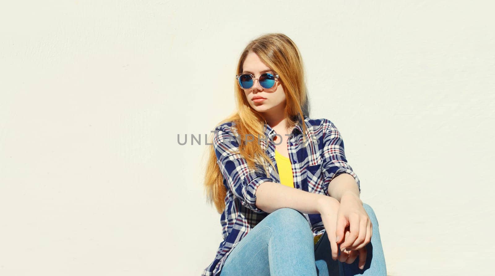Modern caucasian teenager girl in sunglasses posing on city street