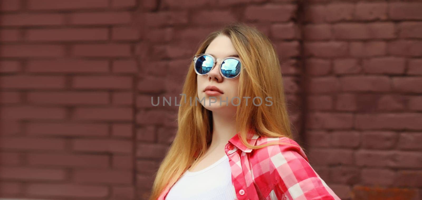 Modern caucasian teenager girl in sunglasses posing on city street