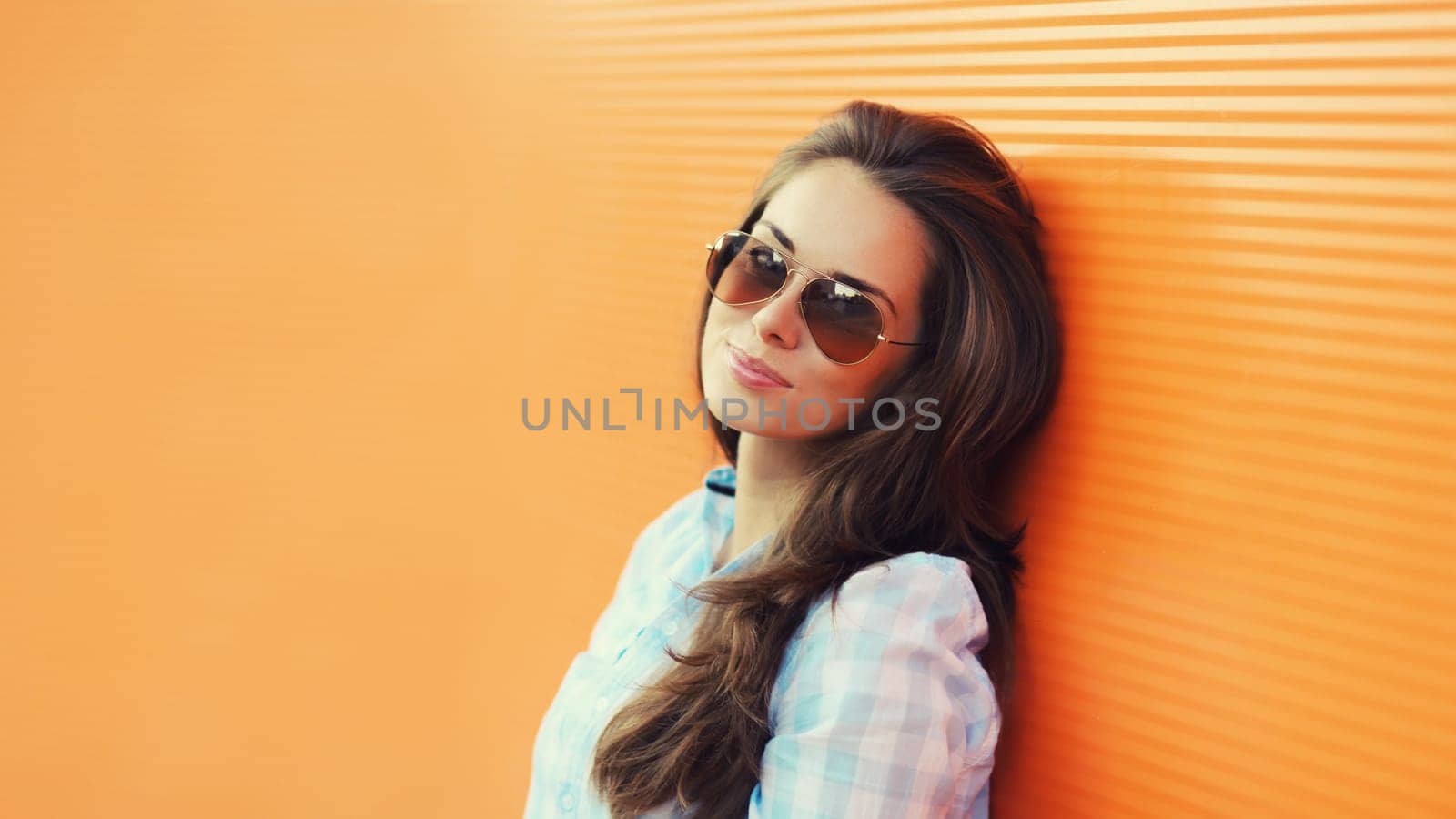 Portrait of beautiful brunette young woman in sunglasses posing in the city