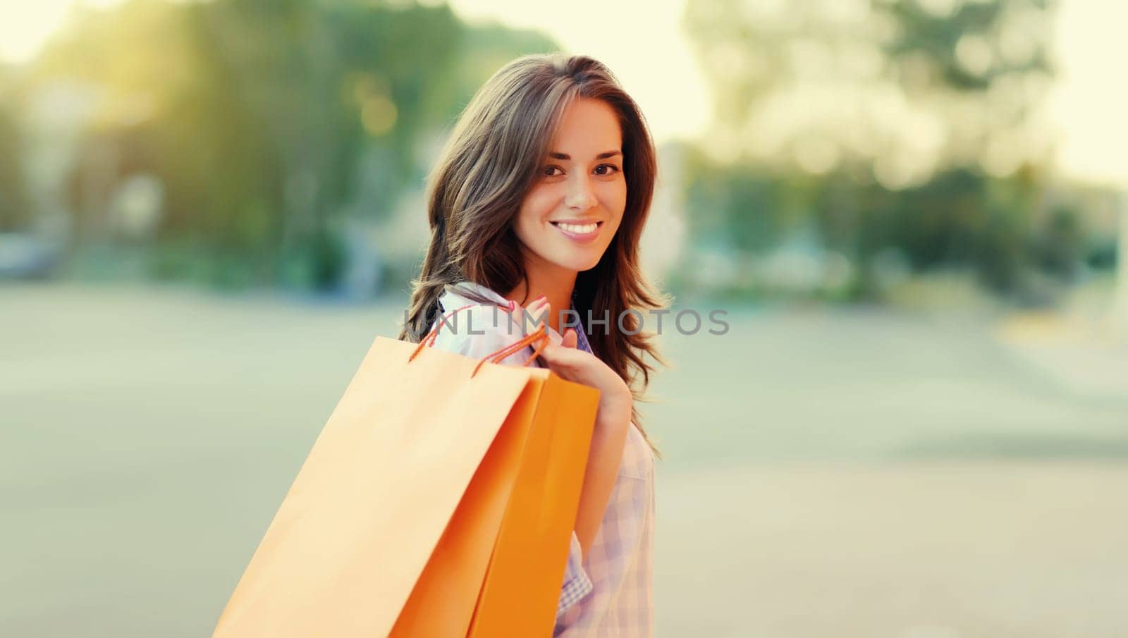 Portrait of happy brunette young woman with shopping bags walking in the city