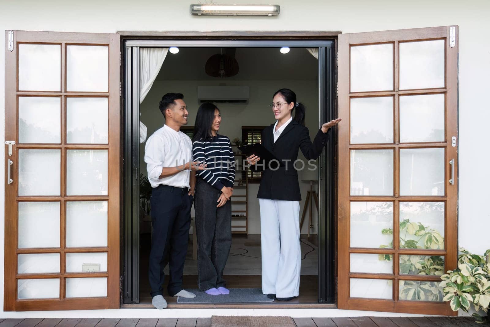 Asian couple looking at house plans and talking with a real estate agent about signing documents for purchase of a new home..