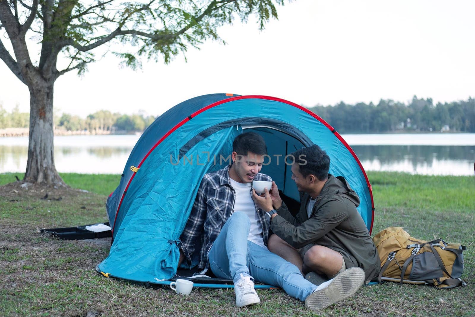 Asian homosexual couple spending their free time on holiday Camp to relax, cook and enjoy the outdoors together. by wichayada