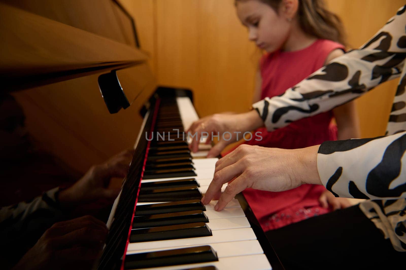 Close-up hands of a woman, pianist teacher giving piano lesson, passionately playing the keys, creating melody, feeling the rhythm of music. Musical education and talent development in progress by artgf