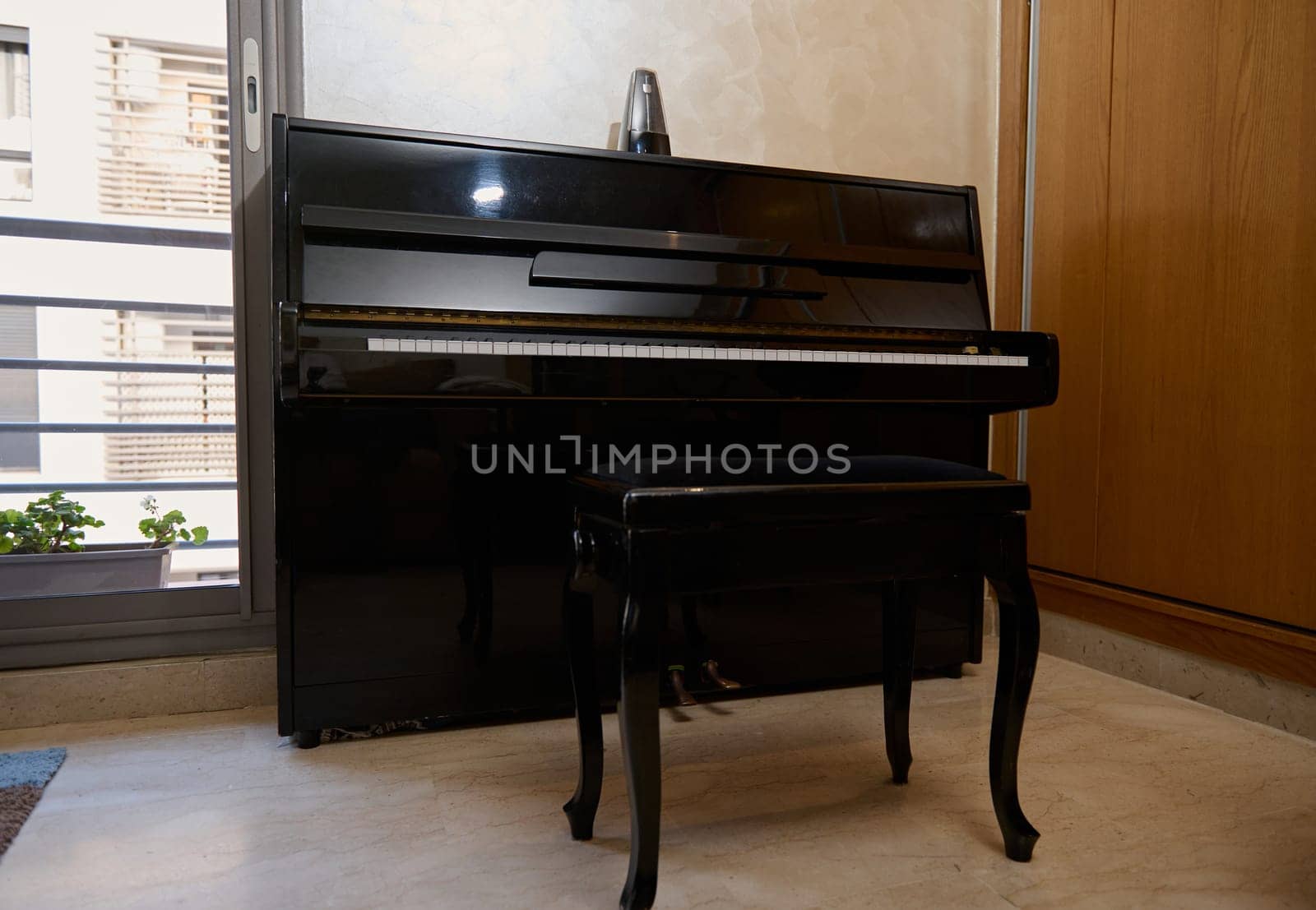 Interior of a room with stylish black piano and backless stool against large window background by artgf