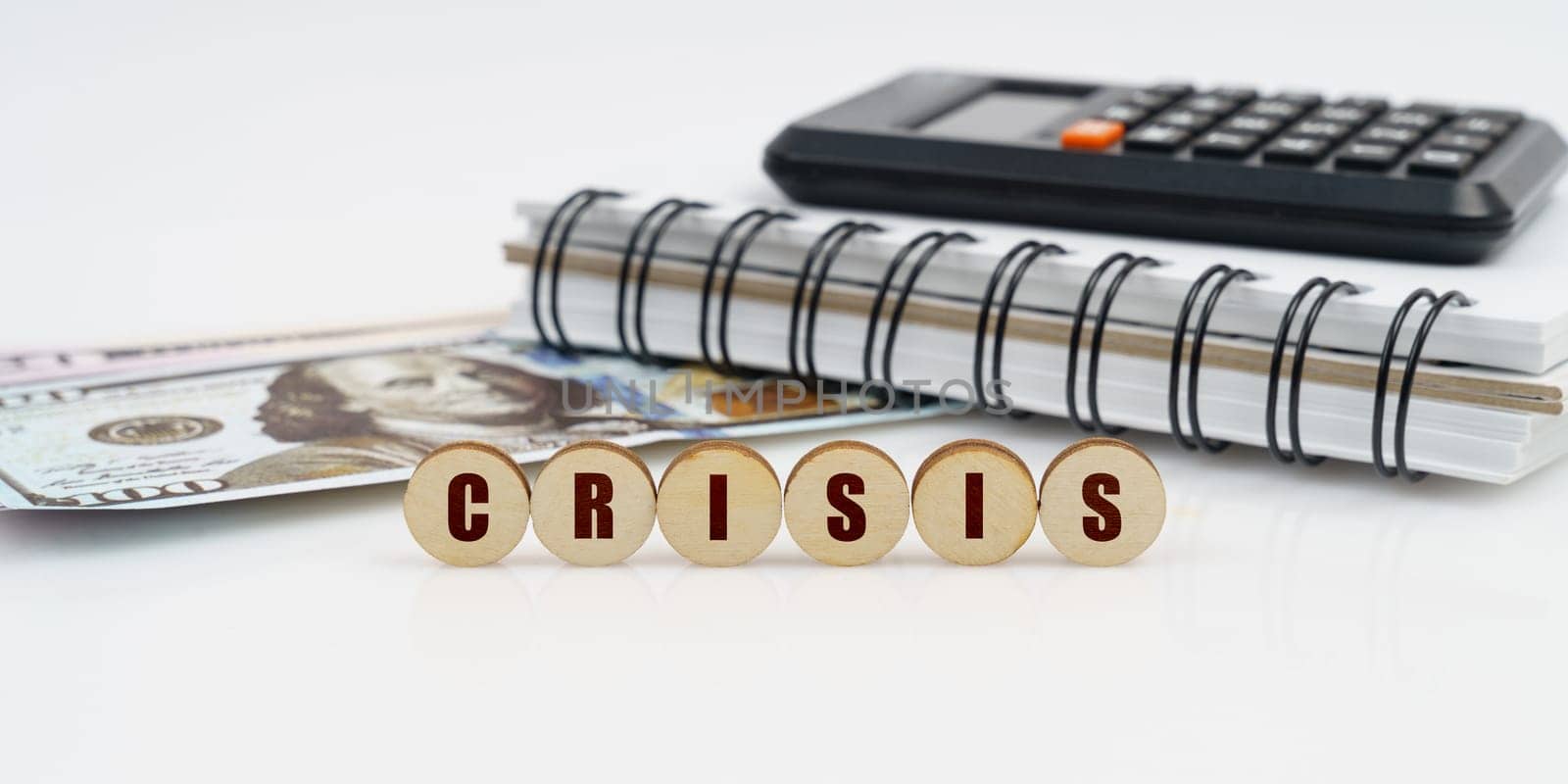 On a high surface lie a notepad, a calculator, dollars and wooden circles with the inscription - CRISIS by Sd28DimoN_1976