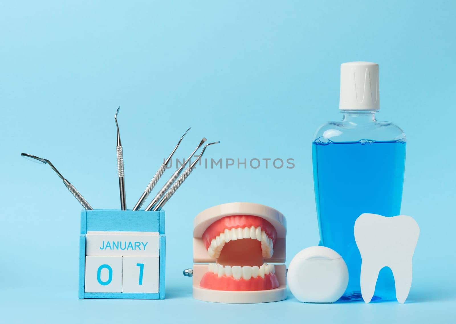 Plastic bottle with mouthwash, dentist medical instruments on blue background by ndanko