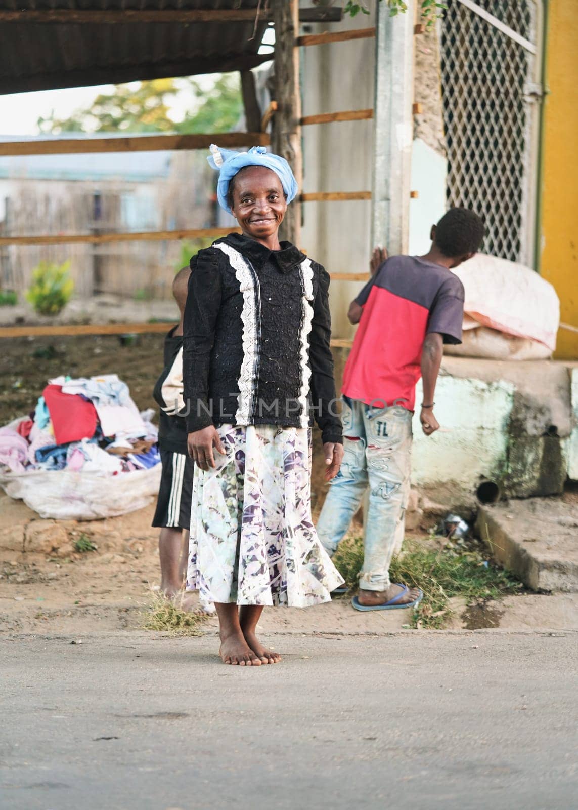 Ranohira, Madagascar - April 29, 2019: Unknown Malagasy woman walking bare feet on main street, she stopped and turned to camera. People of Madagascar are poor but cheerful by Ivanko