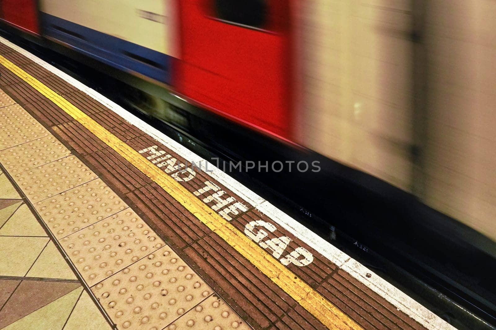 London, United Kingdom - February 02, 2019: MIND THE GAP text on floor of London underground station, blurred train arriving behind white line