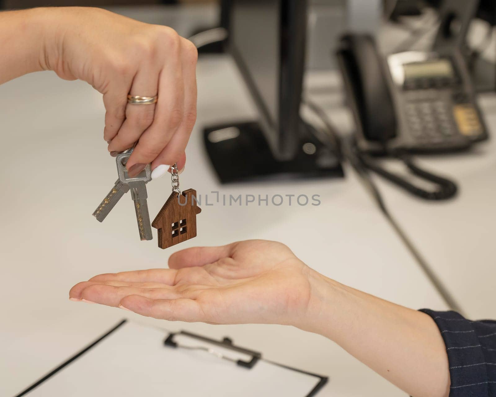 Real estate purchase transaction. The realtor hands the woman the keys to the house. Close-up of hands