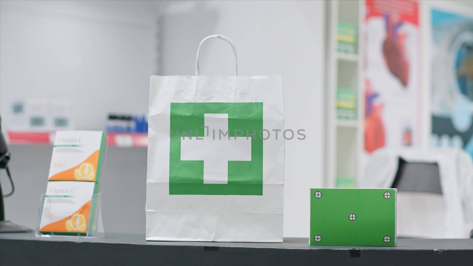 Empty pharmacy with pills and vitamins at cash register, paper bag containing pharmaceuticals alongside greenscreen layer on pill box at checkout area. Chromakey copyspace design next to purchase.