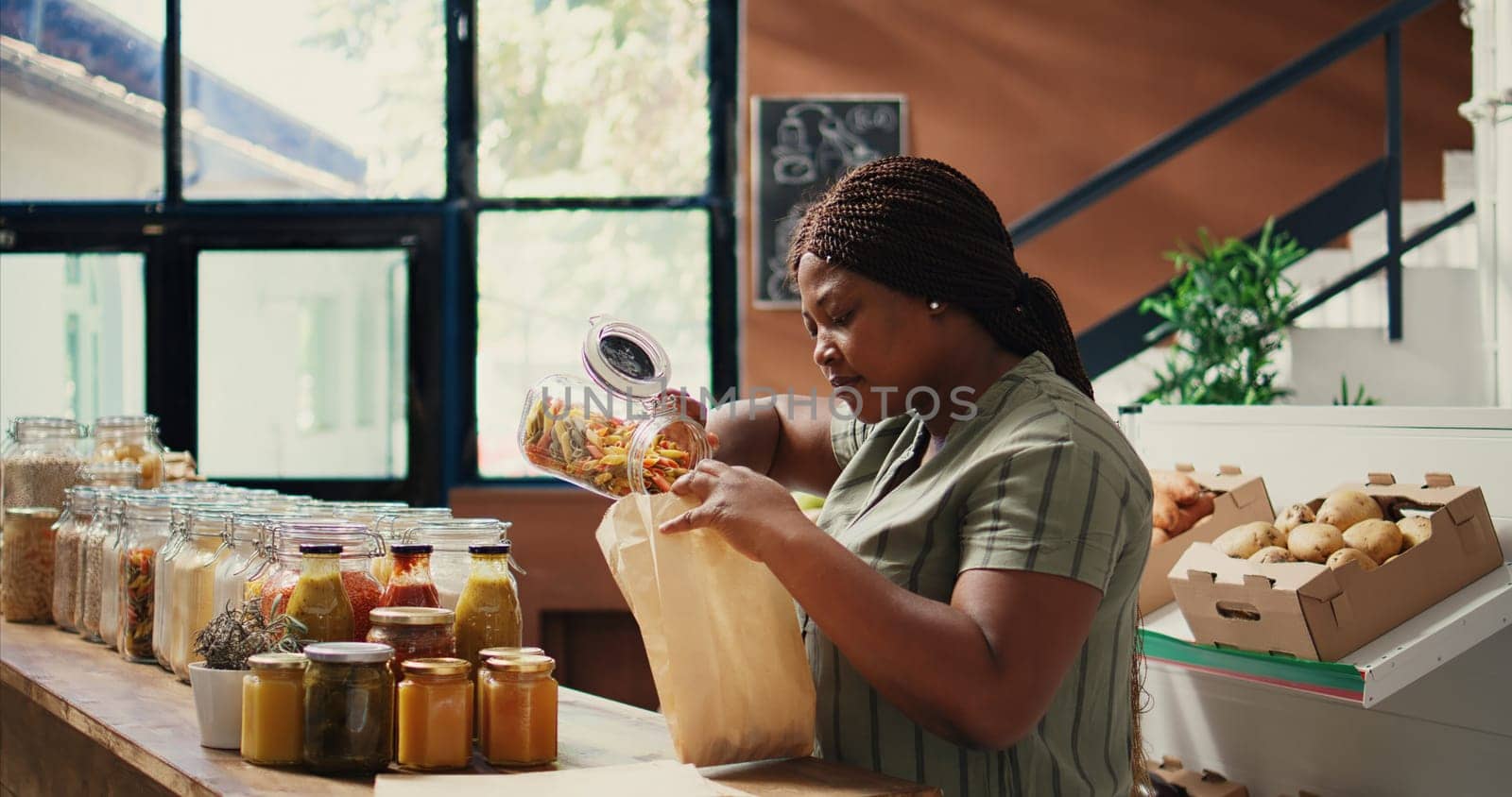 Client pouring pasta in reusable paper bags at zero waste store by DCStudio