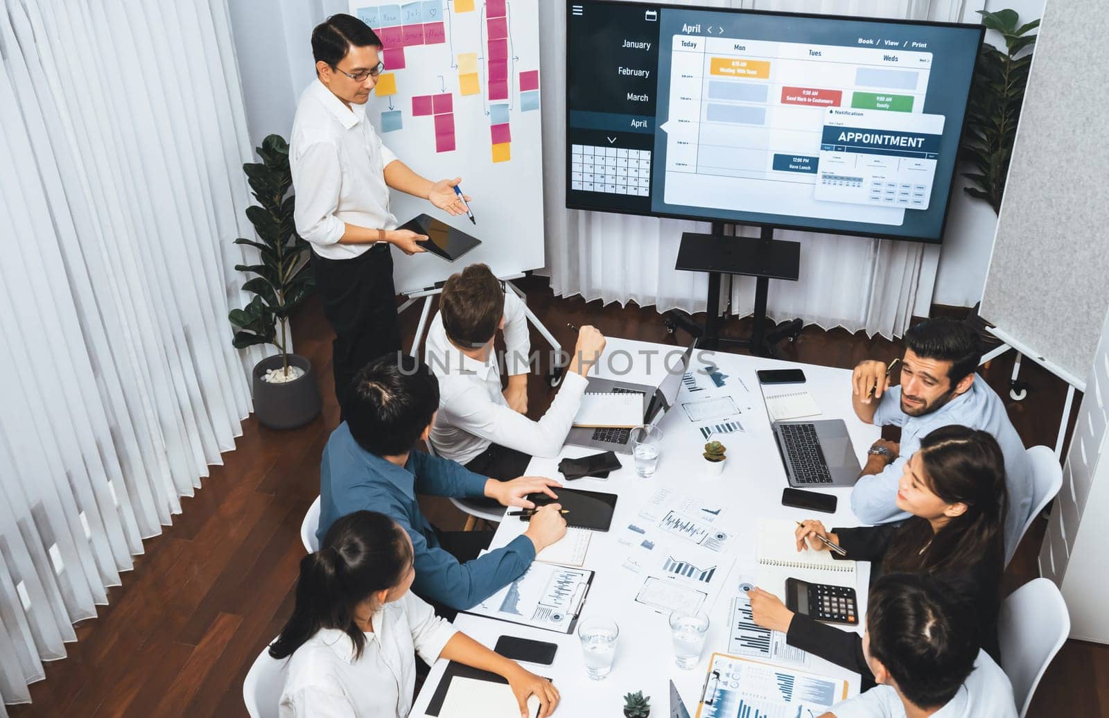 Project manager communicate and collaborate with team using project management software display on monitor, tracking progress of project task and making schedule plan at meeting table. Prudent