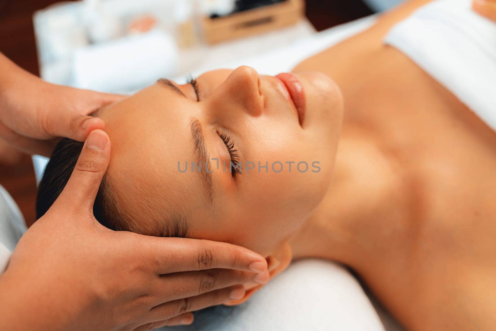 Caucasian woman enjoying relaxing anti-stress head massage and pampering facial beauty skin recreation leisure in dayspa modern light ambient at luxury resort or hotel spa salon. Quiescent