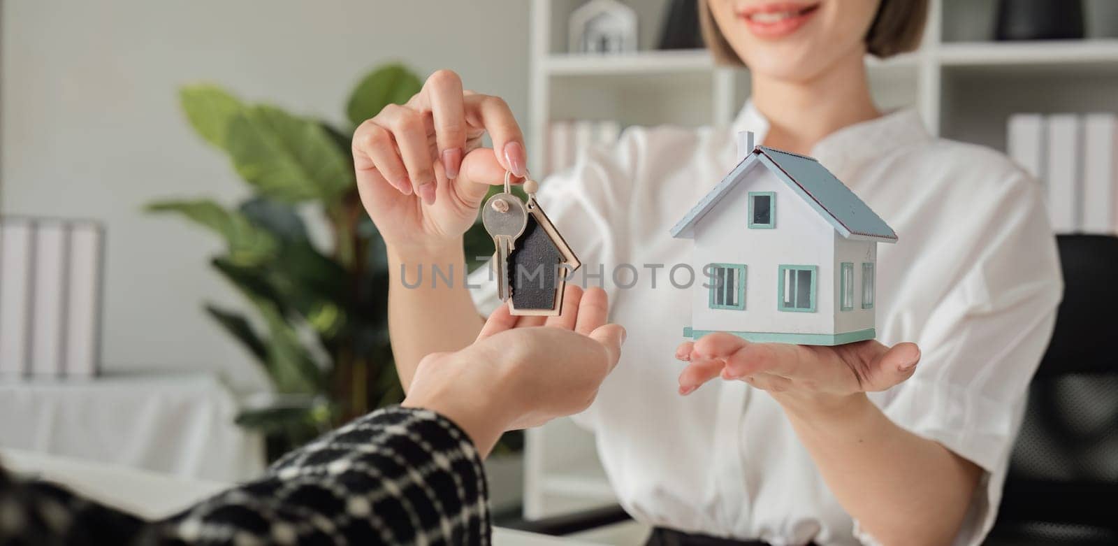 Real estate agent with house plans and keys given to the client after the purchase agreement is reached and the contract is signed. by wichayada