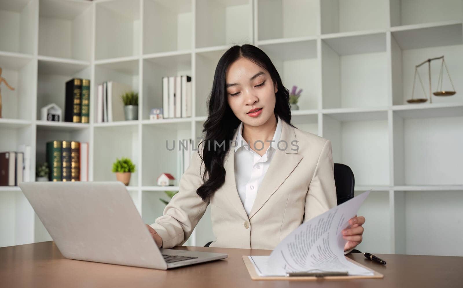 A female Asian lawyer reviews business and real estate laws. Legal consultants provide legal advice and guidance online via laptops in lawyers' offices. by wichayada