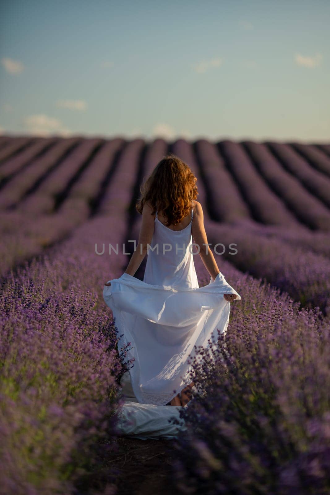 Back view woman lavender sunset. Happy woman in white dress holds lavender bouquet. Aromatherapy concept, lavender oil, photo session in lavender by Matiunina