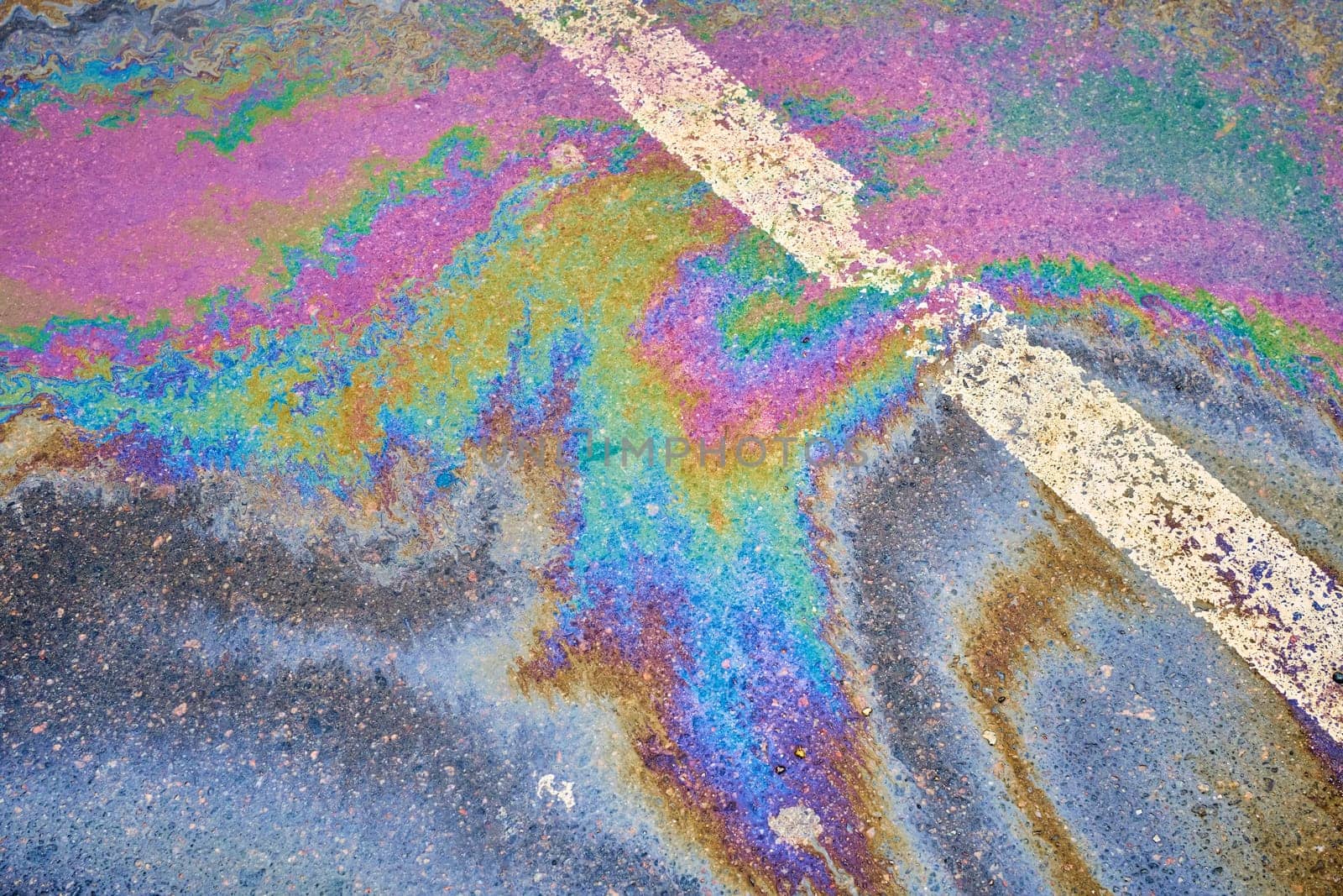 Oil spill on wet asphalt, parking lot with dividing lines. Highlighting environmental challenges related to water pollution