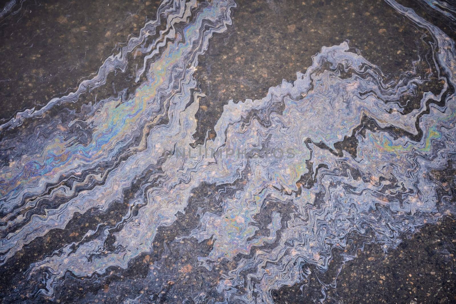 Marble spills on the water from stains of gasoline and oil. Abstract background from motor oil, gas or petrol spilled on asphalt. Water with patches of gasoline and oil