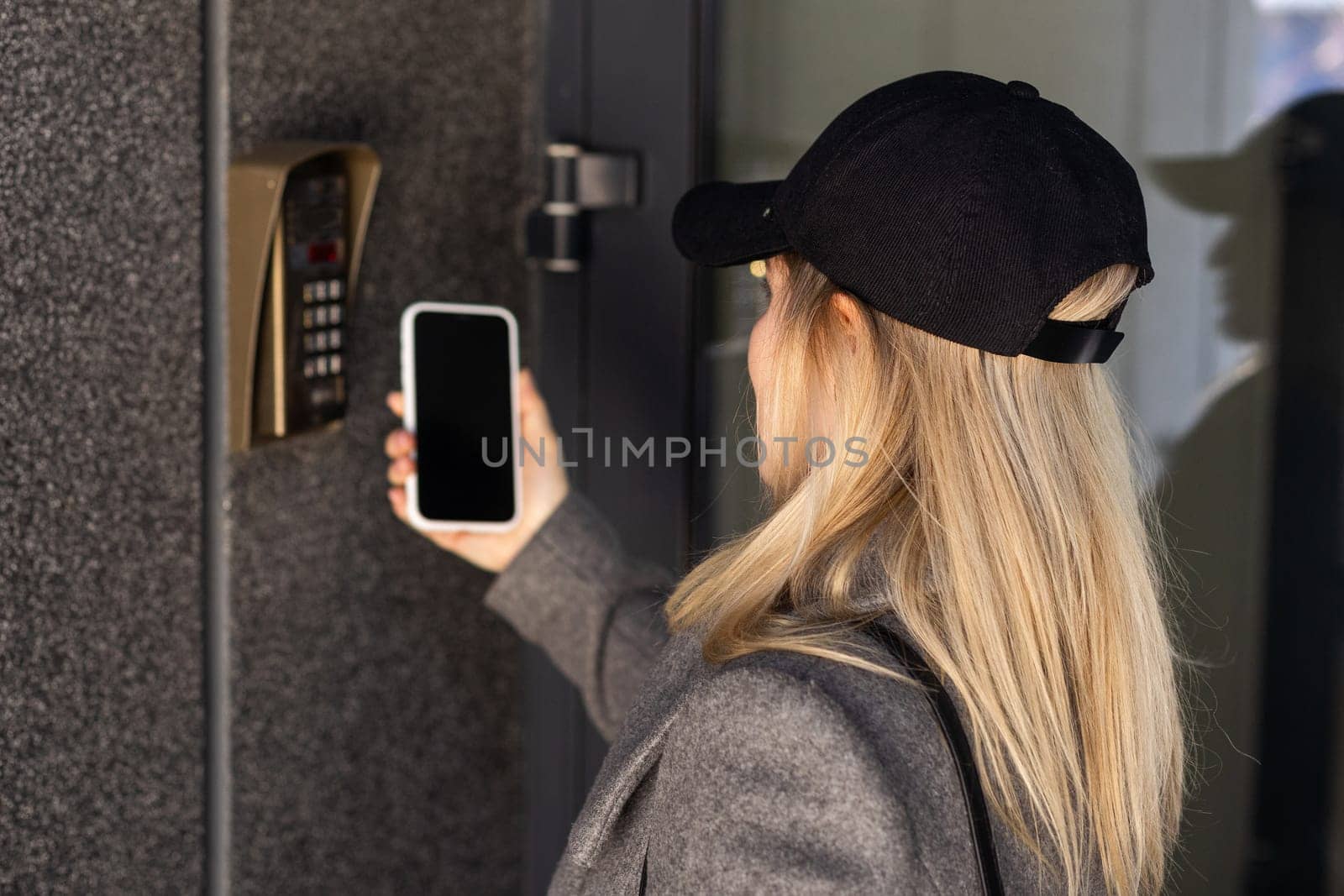 Woman locking smartlock on the entrance door using a smart phone. Concept of using smart electronic locks with keyless access. by Andelov13