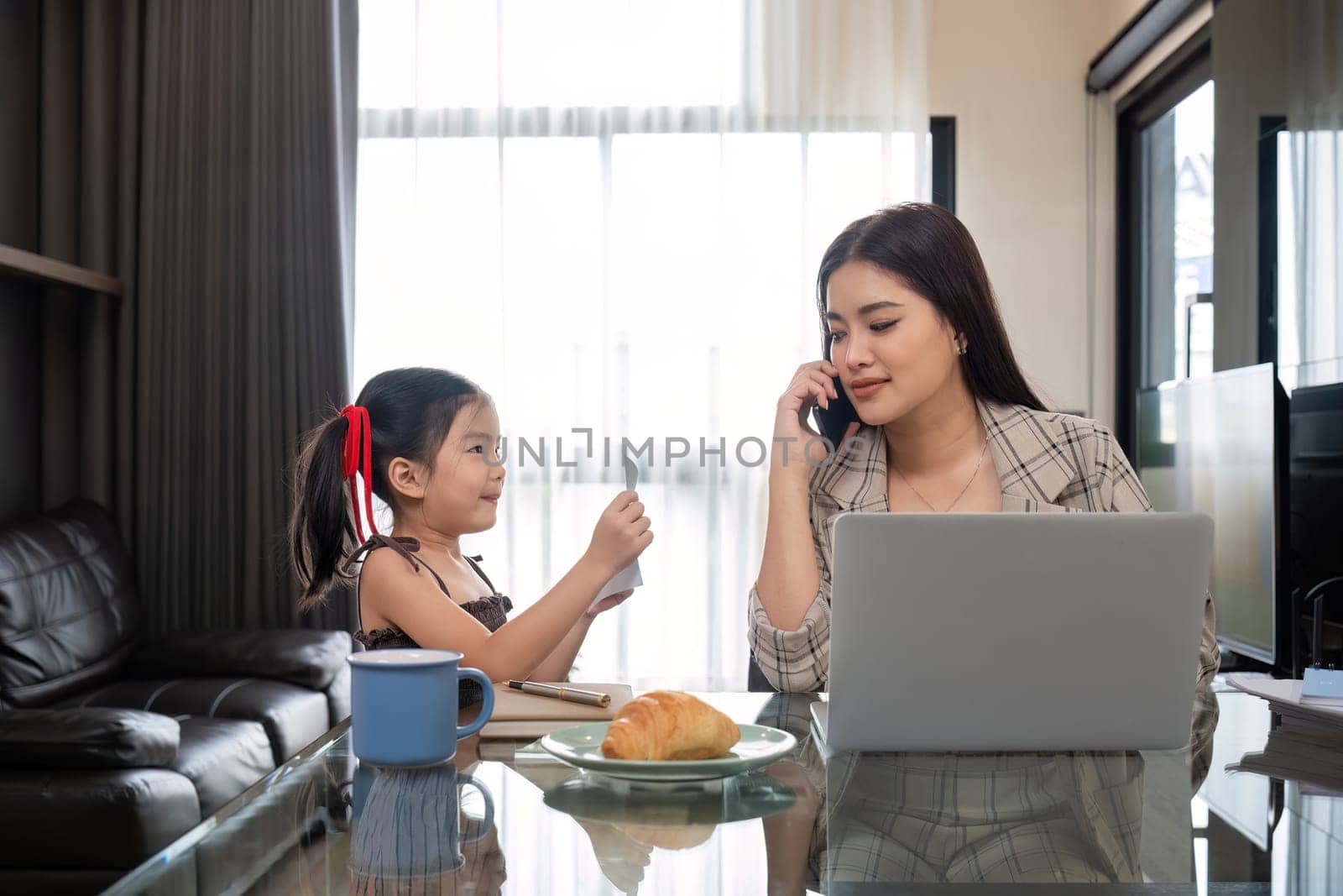 The young woman works from home, raises her daughter, and discusses work with co-workers on the phone and online..