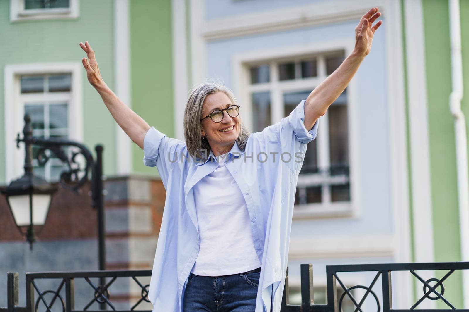 Woman With Arms Outstretched in Front of Building by LipikStockMedia