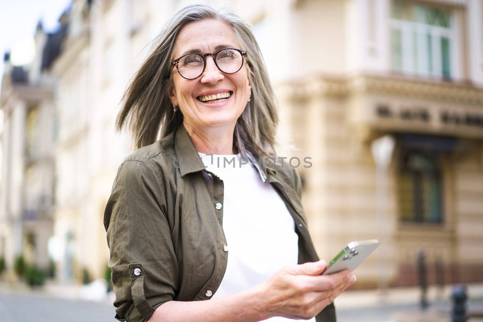 Woman With Glasses Holding Cell Phone by LipikStockMedia