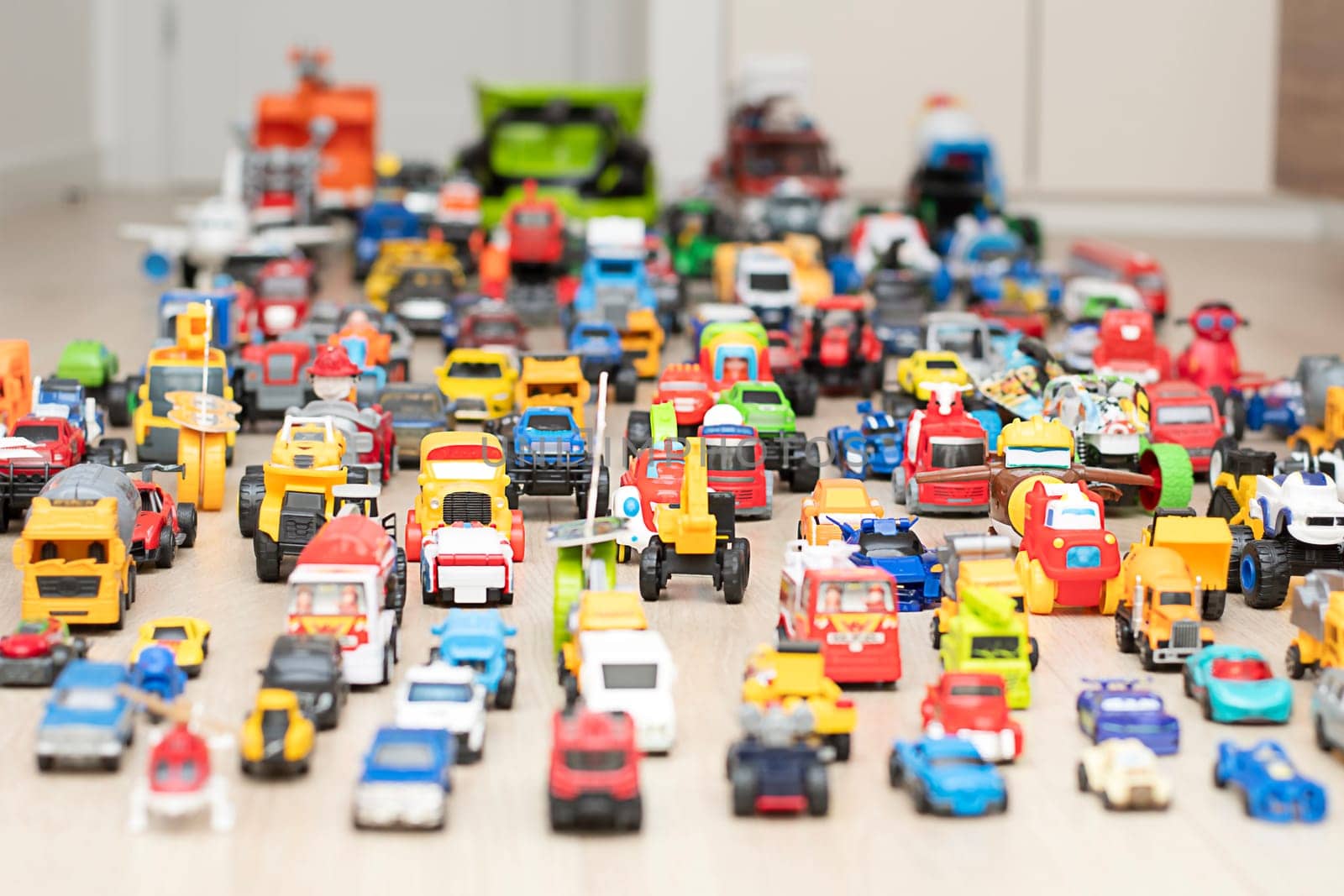 Toy cars, motorcycles, tractors, buses, pickups, many colorful small and large cars are arranged for play on the floor in the children's room. Childhood concept. soft focus.