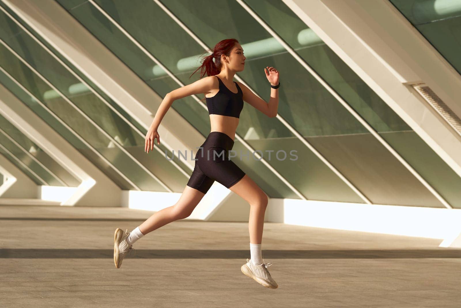 Athletic woman in sportswear is jogging around the city in early morning. Reaching the goal