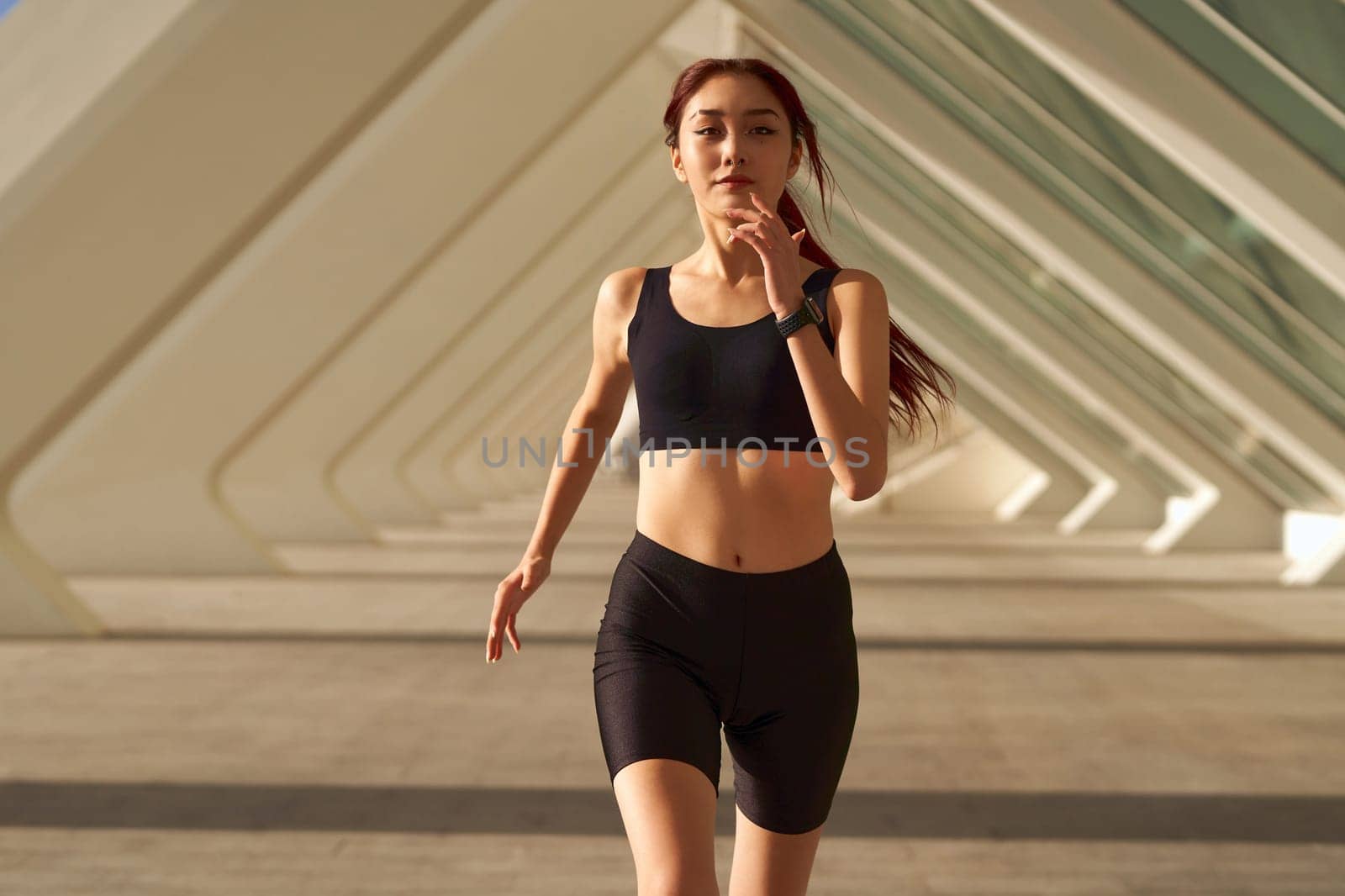 Athletic woman in sportswear is jogging around the city in early morning. Reaching the goal