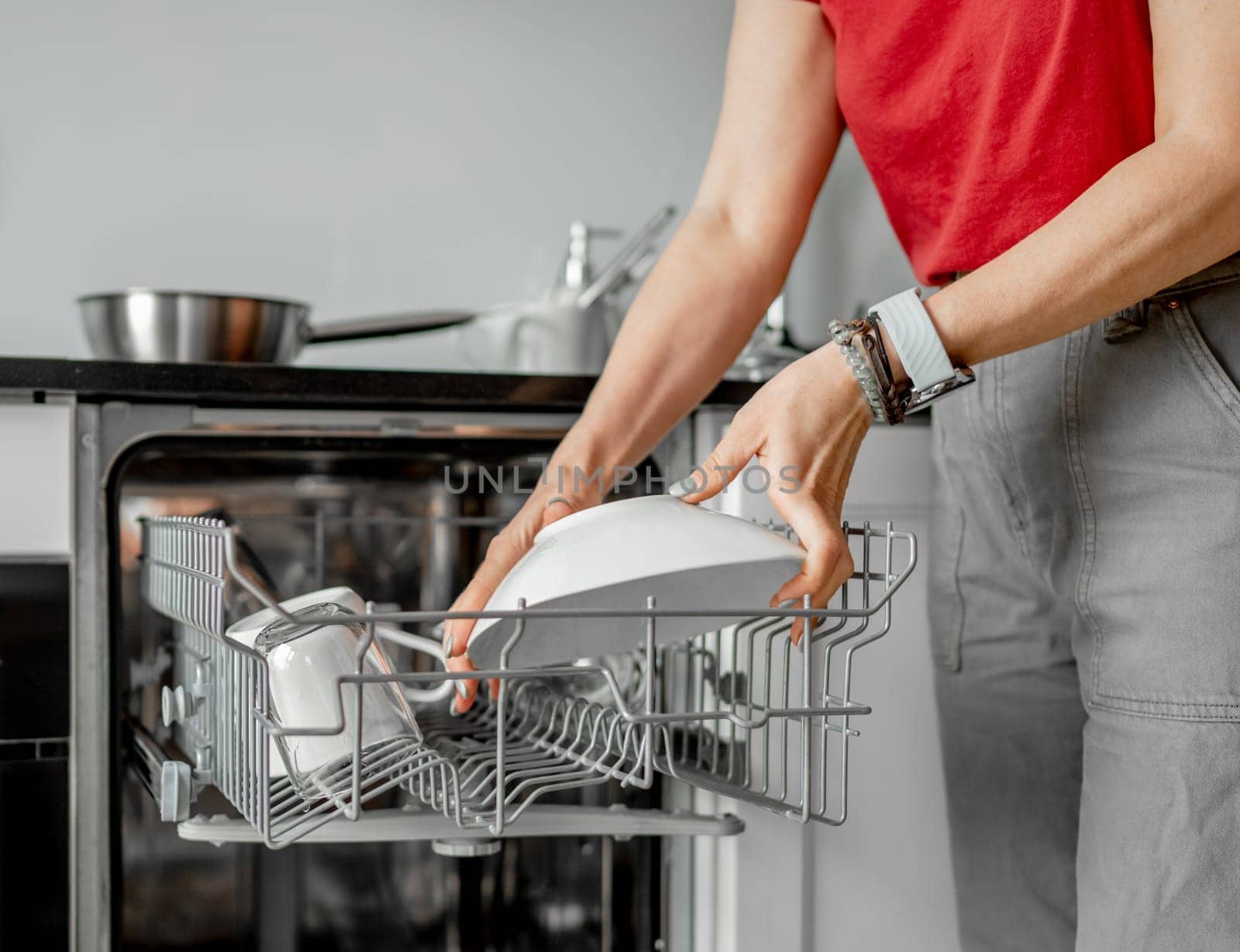 Young Woman Takes Out Clean Dishes From Dishwasher In Close-Up Shot