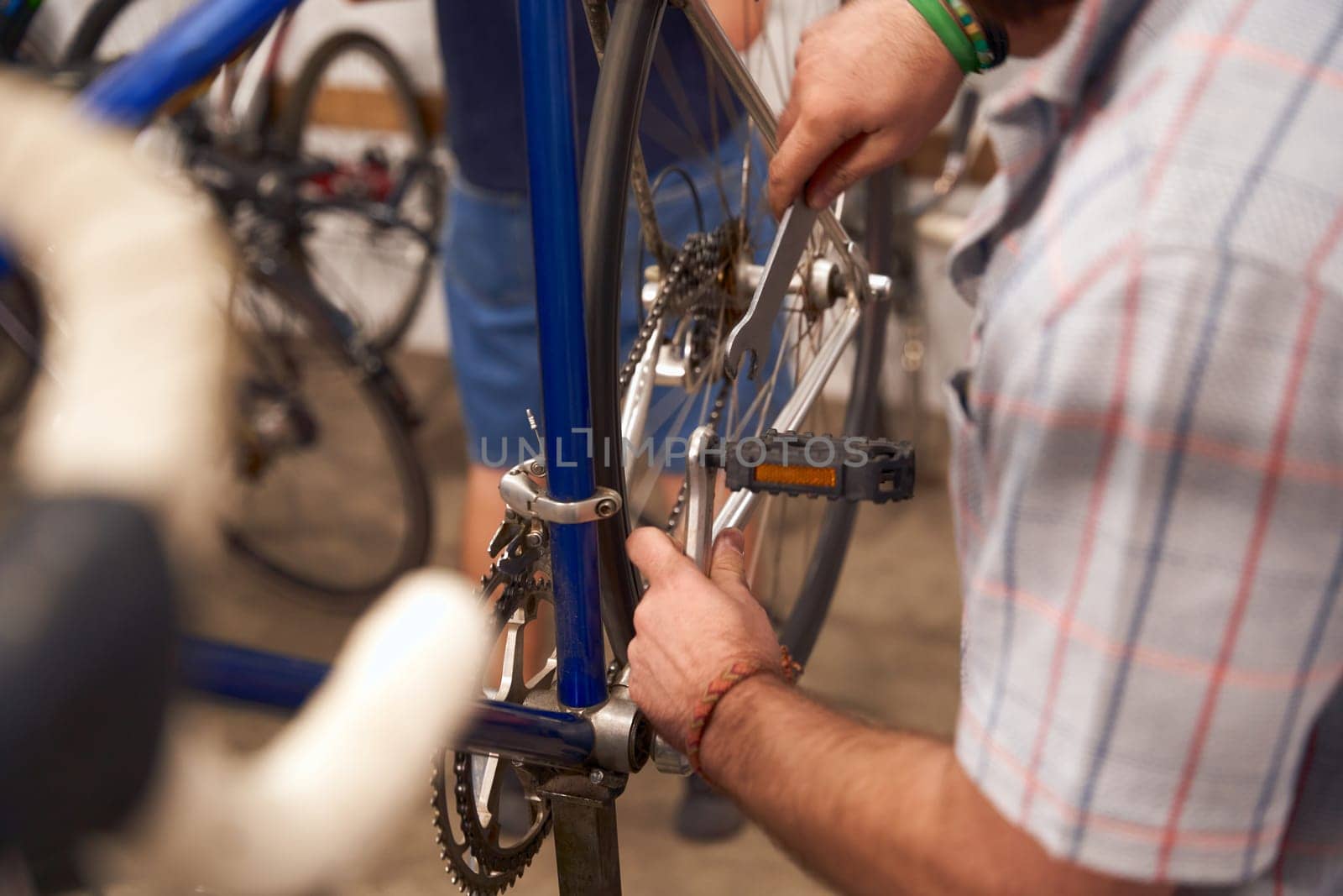 Close up of serviceman repairing modern bike using special tool while working in workshop by Yaroslav_astakhov