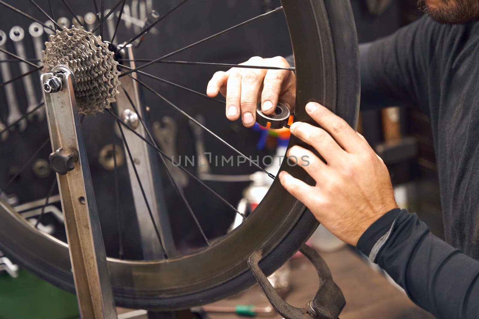 Close up of man working in a bicycle repair shop and checking the wheel of the bike