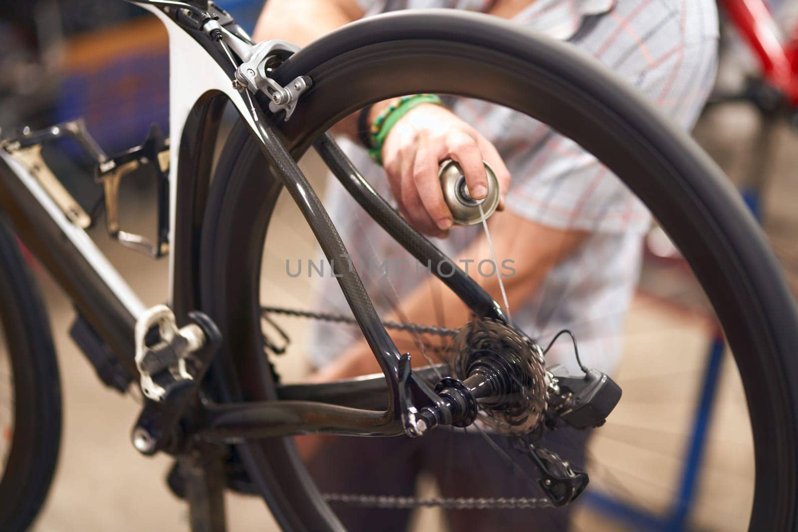 Close up of repairman is lubricate the bike chain in workshop. High quality photo