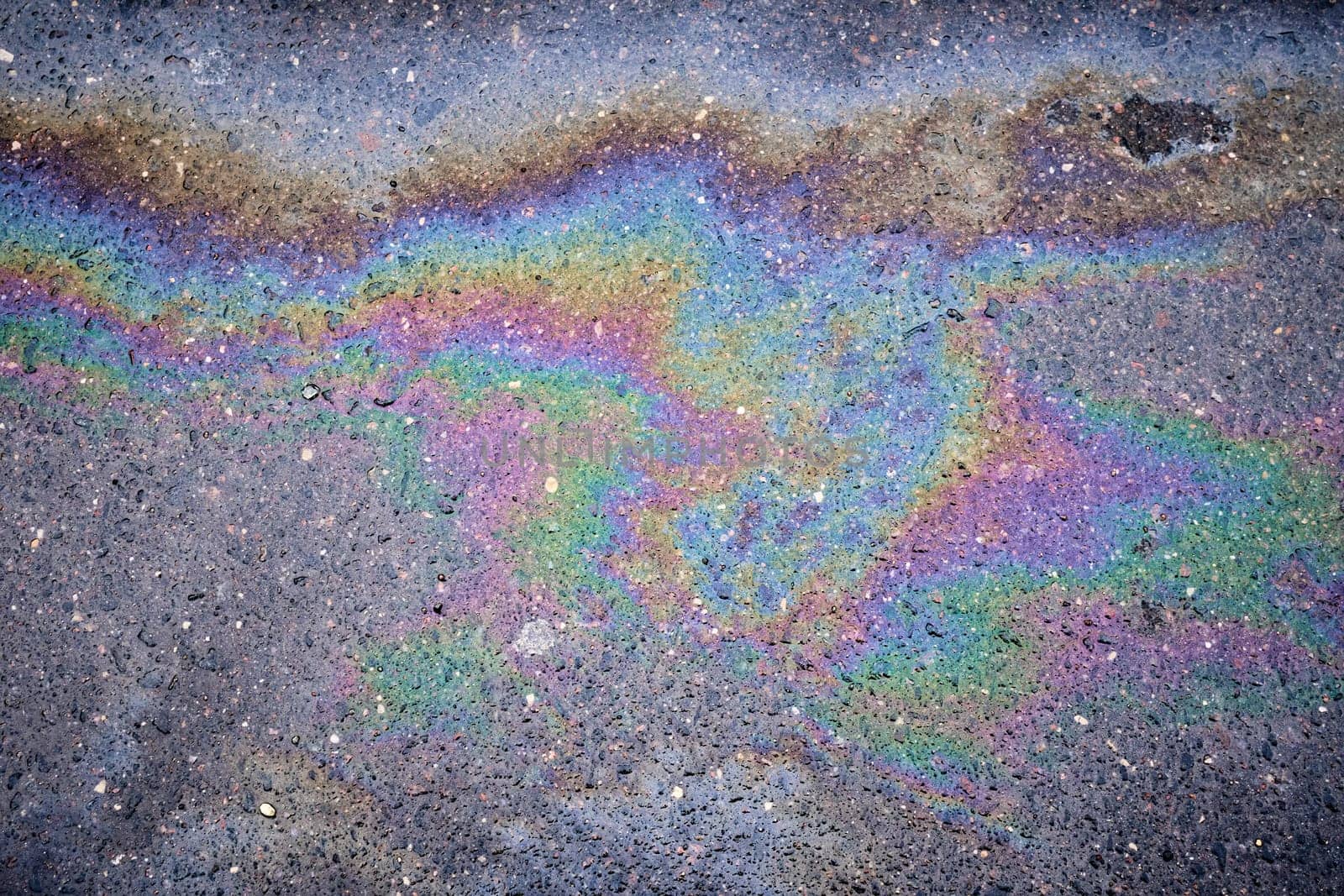 Textured stain of fuel or oil on wet asphalt on a rainy day. The concept of environmental pollution.