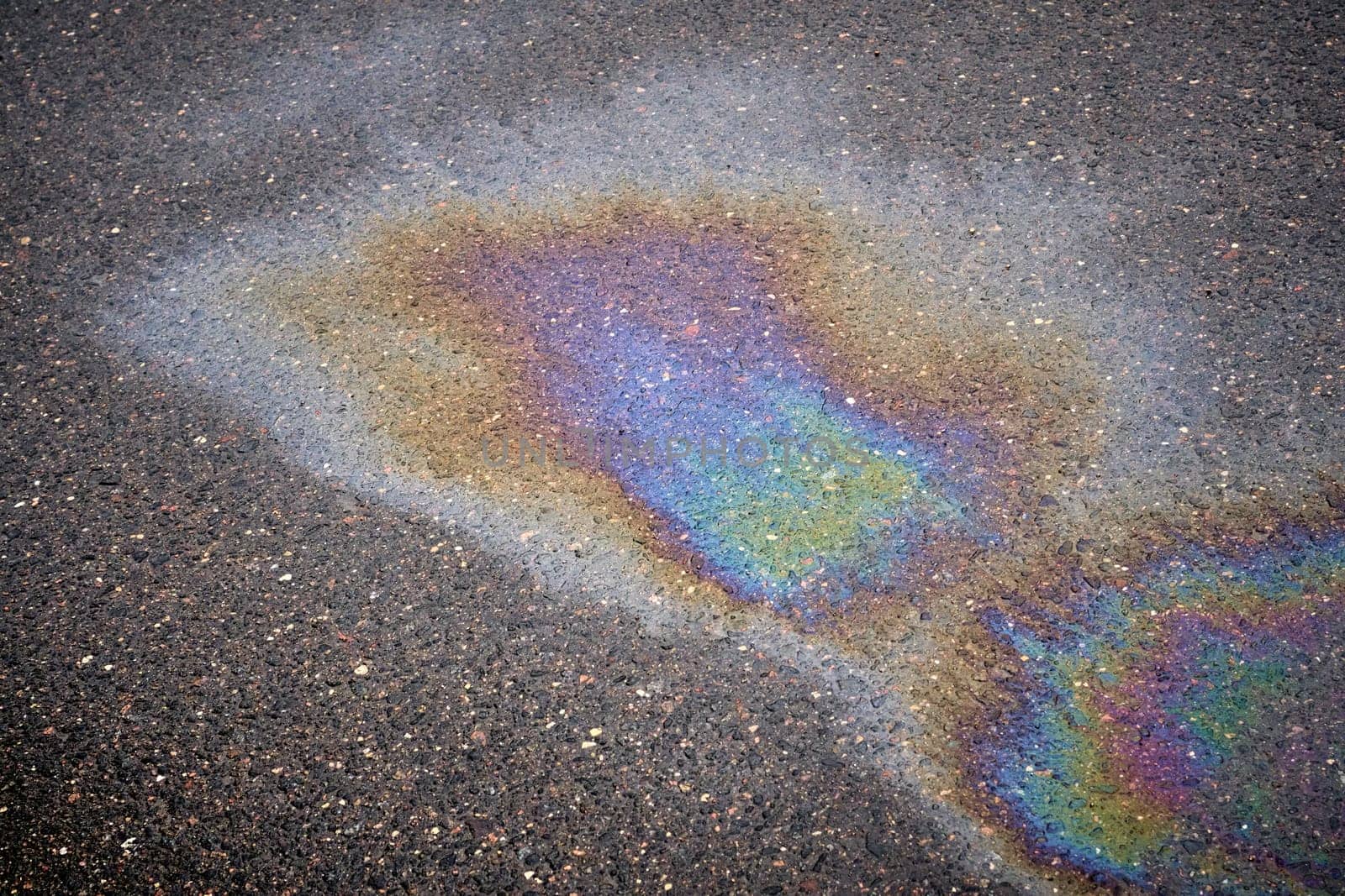 Fuel or oil stain with texture on wet asphalt under rainy conditions, symbolizing environmental pollution