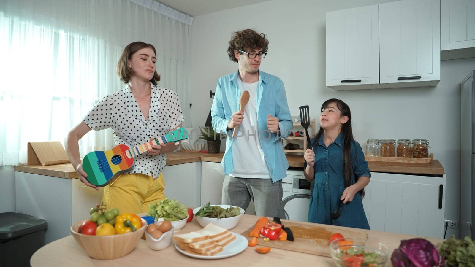 Father, mother and daughter making breakfast while dancing together. Pedagogy. by biancoblue