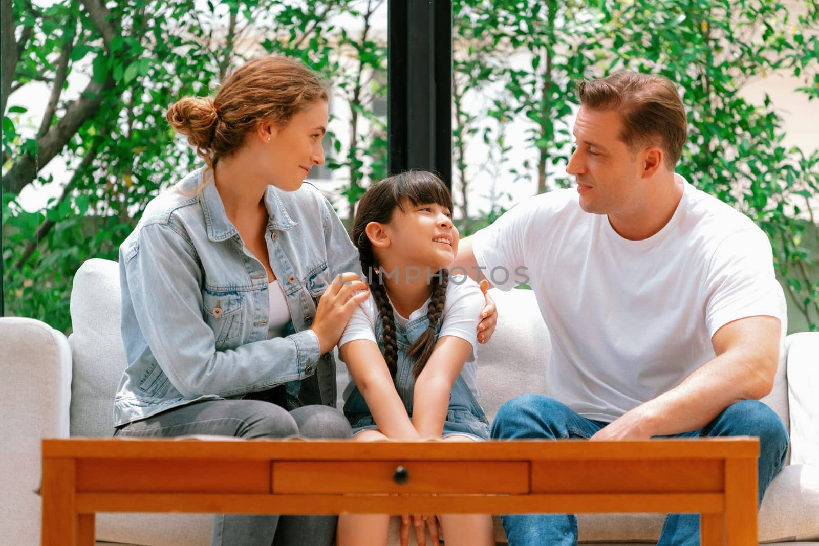 Parents comforting their daughter with loving hug, helping her feel secure and protected from fear, rest her head on shoulder. Happy family love and child care support concept. Synchronos