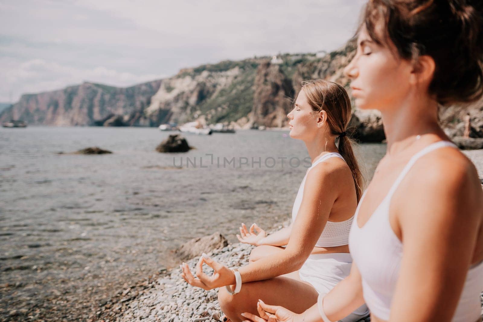 Woman sea yoga. Happy women meditating in yoga pose on the beach, ocean and rock mountains. Motivation and inspirational fit and exercising. Healthy lifestyle outdoors in nature, fitness concept. by panophotograph