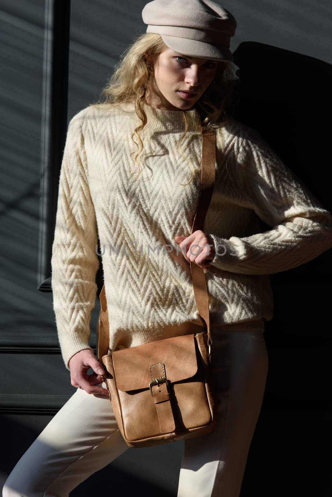 Studio portrait of beautiful woman with a curly blond hair holding brown bag, posing on gray background. by Ashtray25