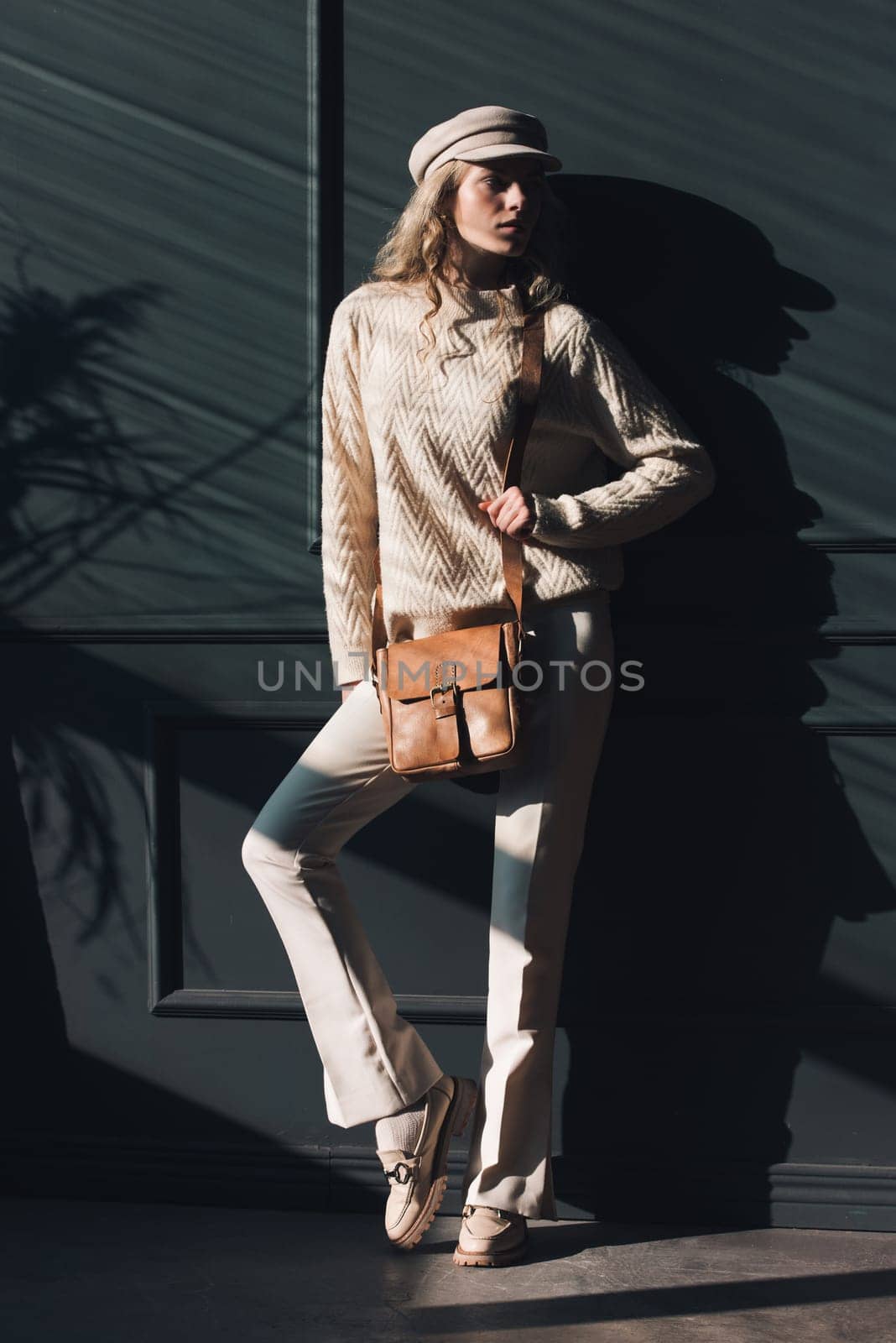 Studio portrait of beautiful woman with a curly blond hair holding black bag, posing on gray background. by Ashtray25