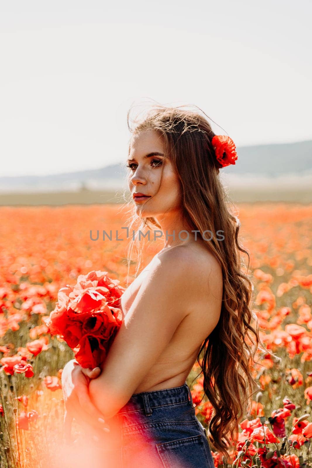 Woman poppies field. portrait of a happy woman with long hair in a poppy field and enjoying the beauty of nature in a warm summer day