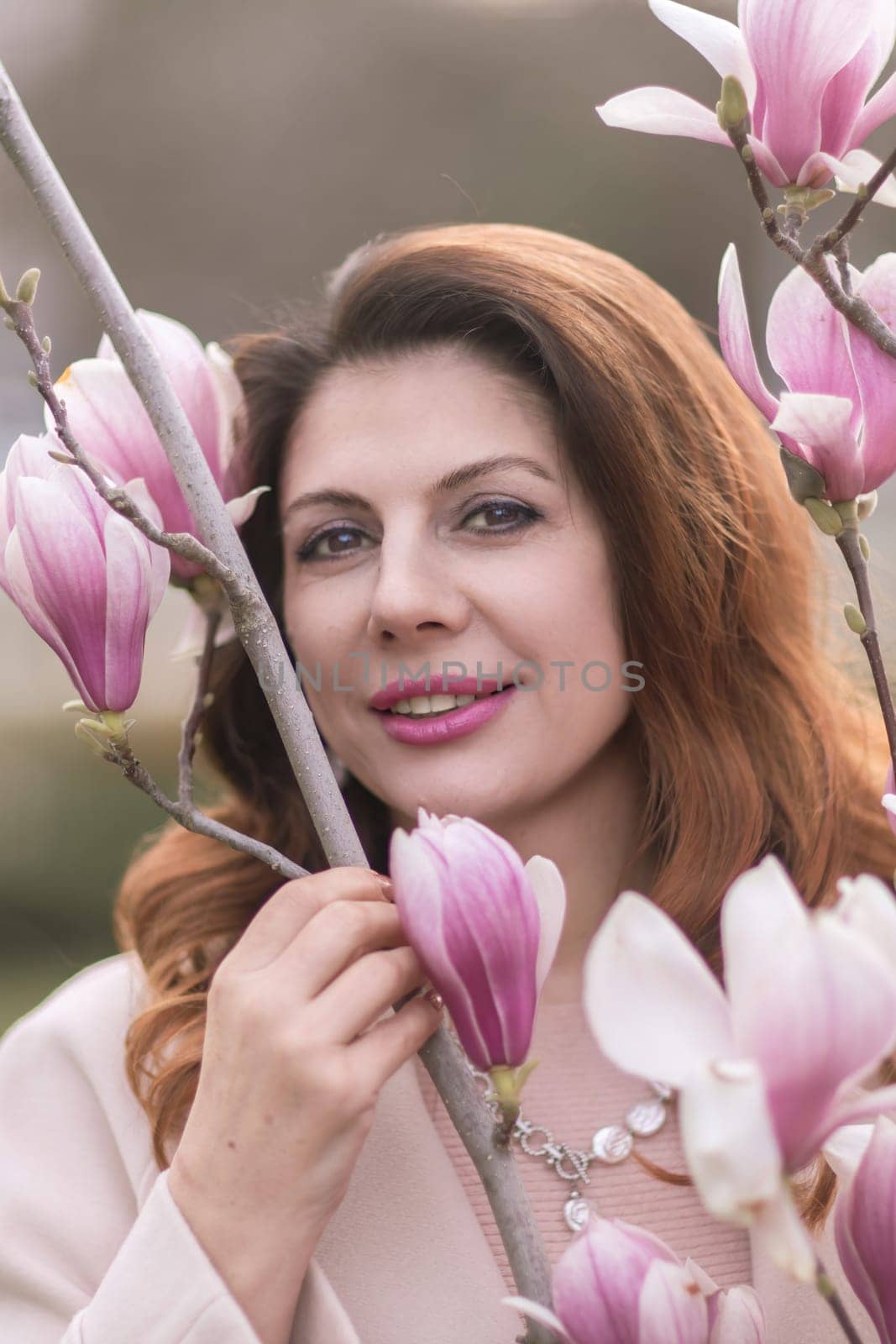 Woman magnolia flowers, surrounded by blossoming trees, hair down, wearing a light coat. Captured during spring, showcasing natural beauty and seasonal change