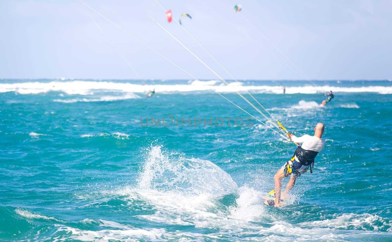 Kiteboarding. Fun in the ocean. Extreme Sport Kitesurfing. Kitesurfer jumping high in the air performing triks during kitesurfing session. by kasto