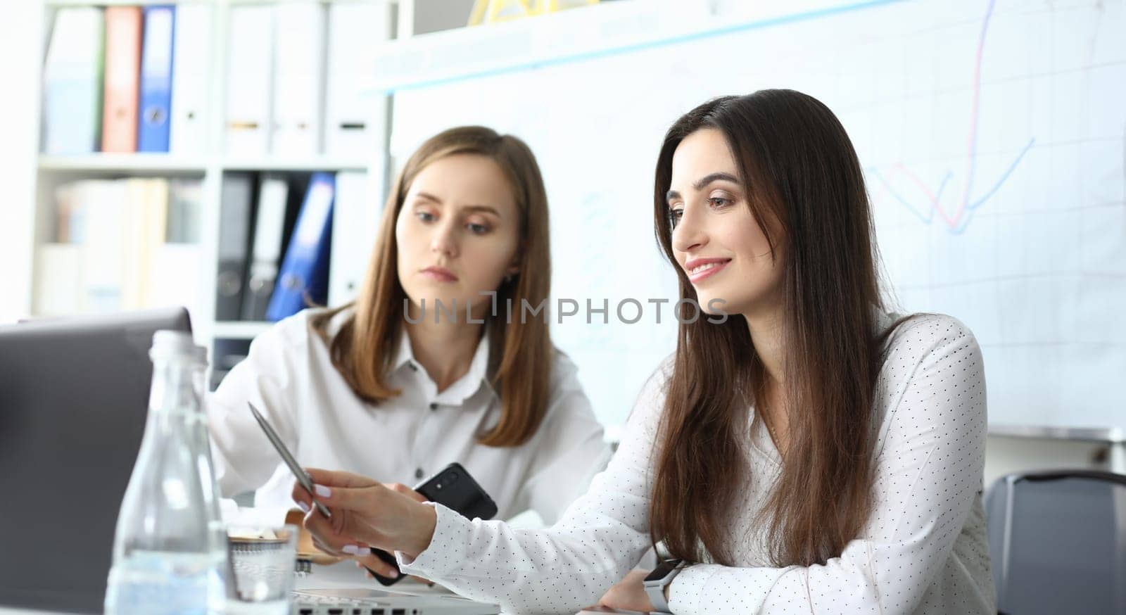 Portrait of gorgeous businesswoman sitting in modern workplace and showing something on screen of high-tech laptop and discussing important topic. Accounting office concept