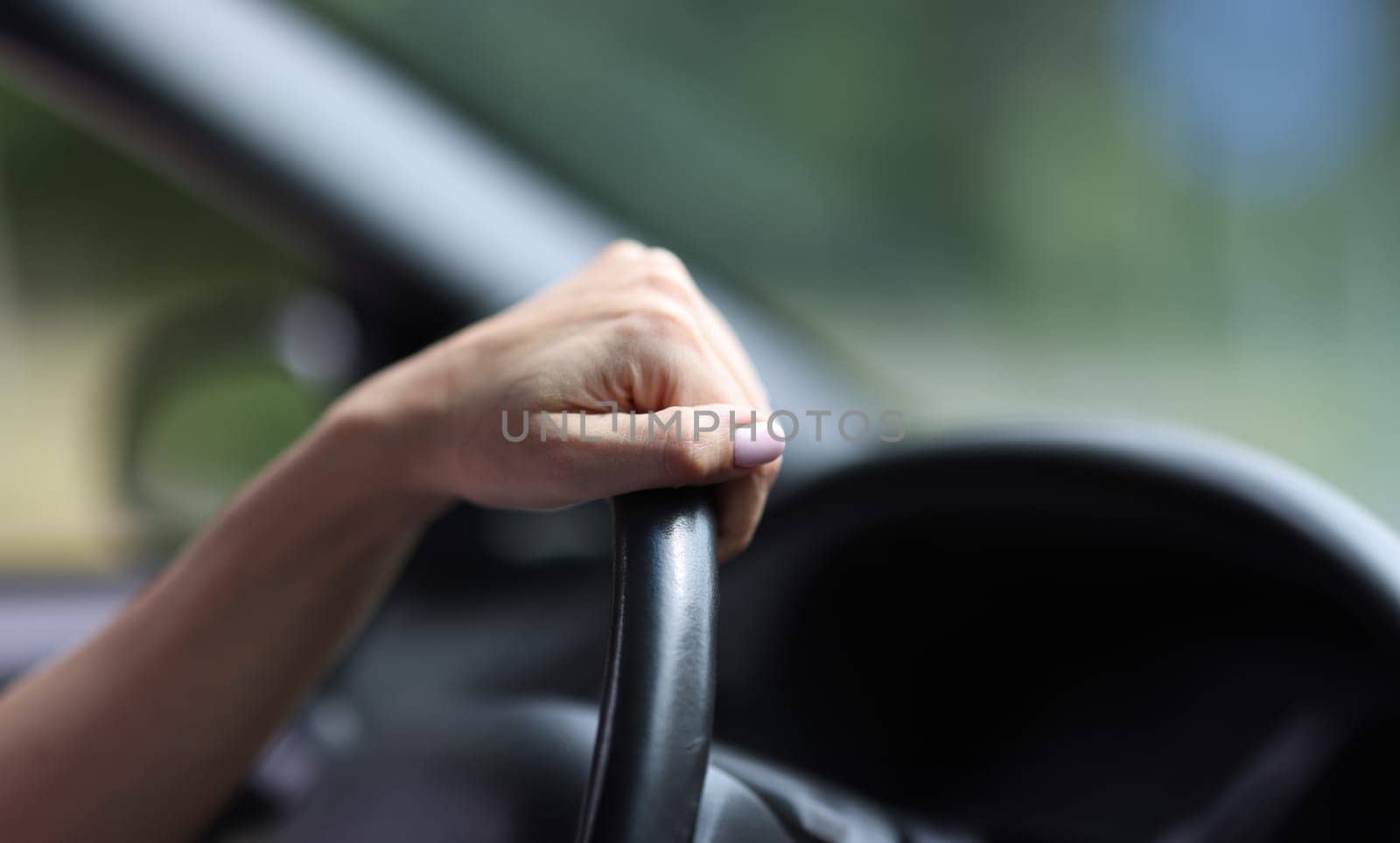 Female hand hold leather steering wheel in car. by kuprevich